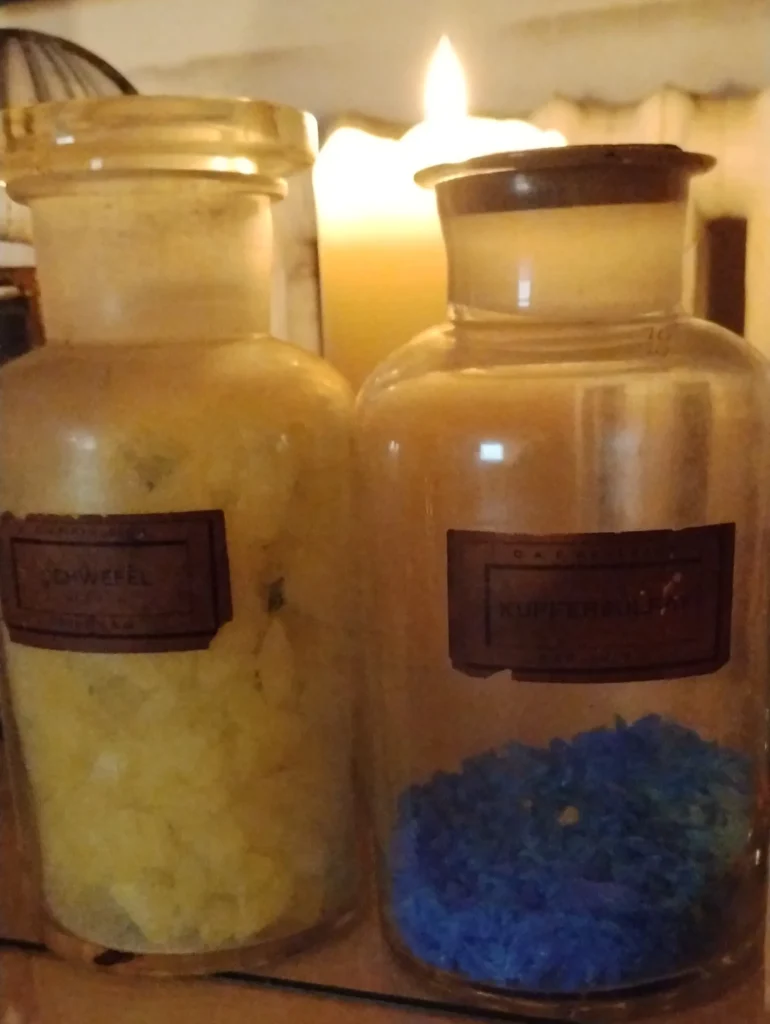 Bocaux en verre contenant du soufre et du sulfate de cuivre, pigments utilisés dans les pratiques alchimiques et les vitraux à Suhalia.
